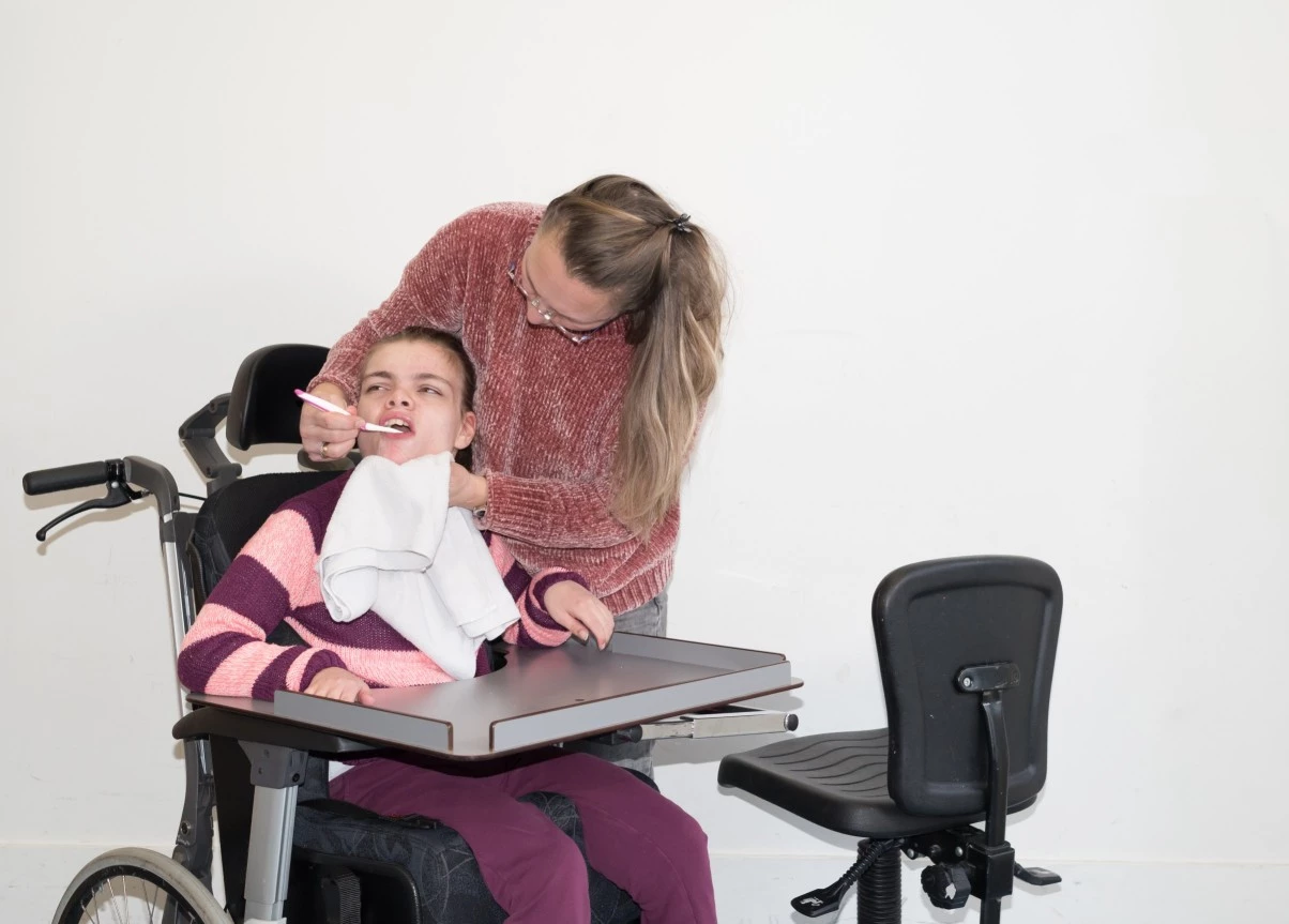 Nurse spoon feeding a disabled girl on wheelchair