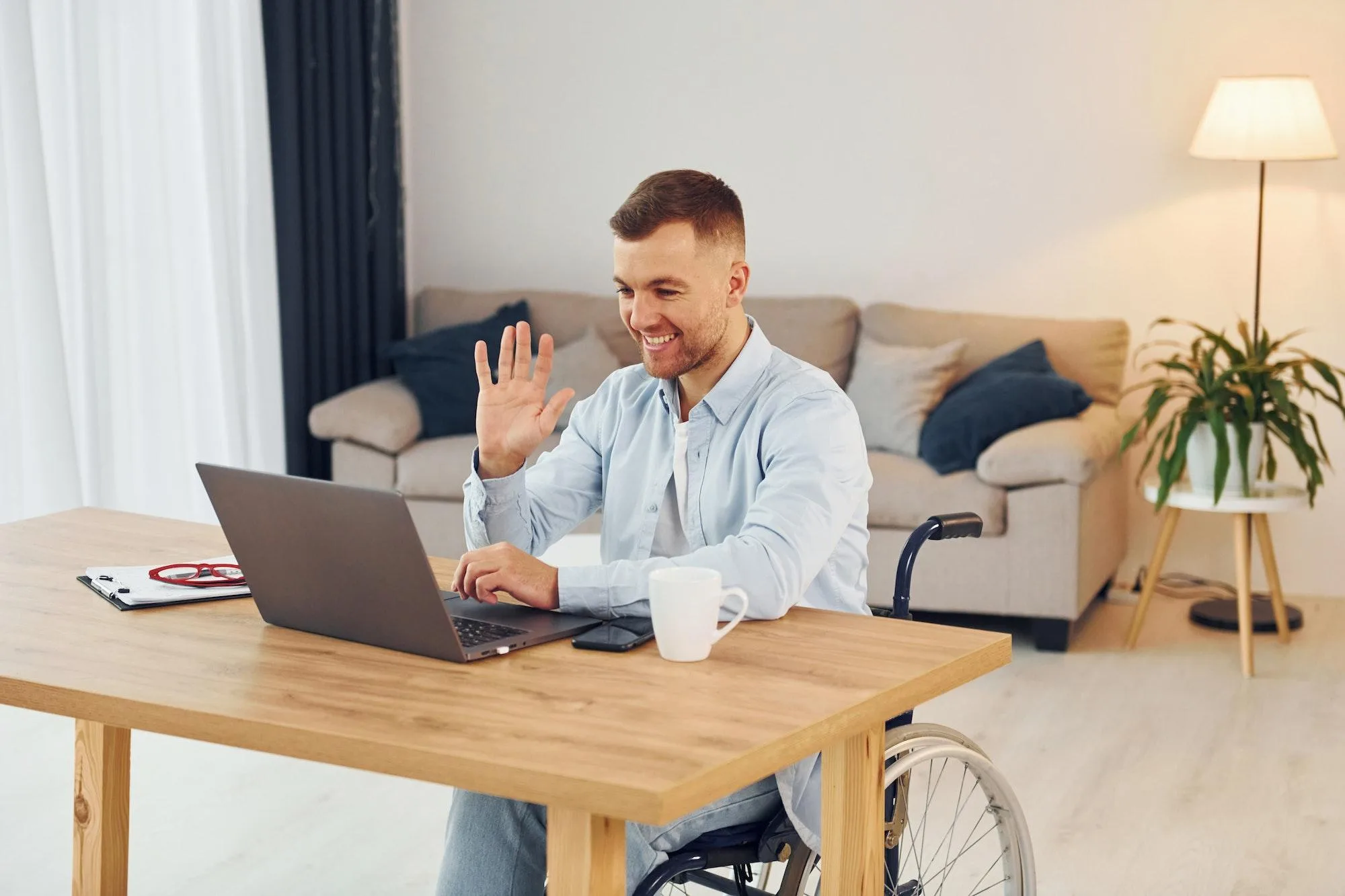 laptop on the table disabled man in wheelchair is at homee