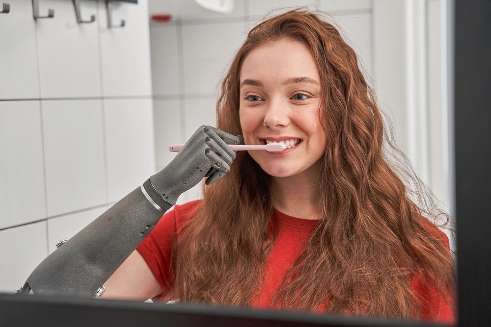 Women brushing her teeth with a prosthetic arm