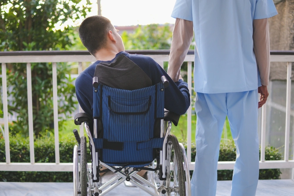 Nurse with a disabled boy on wheelchair in balcony looking at nature